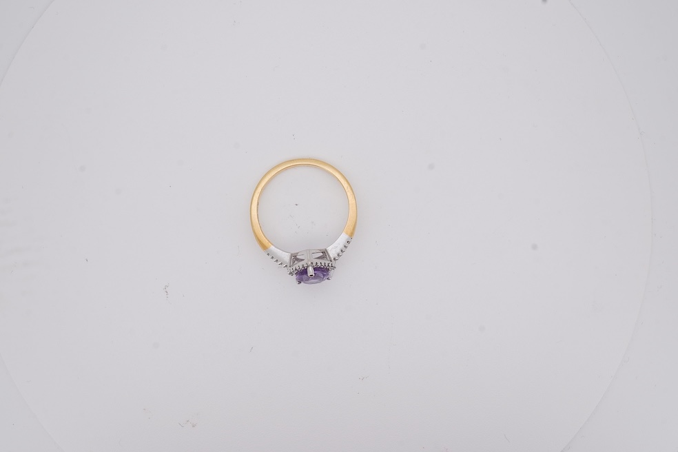A modern 18ct gold and single stone pear cut amethyst set ring, with diamond chip set border and shoulders, size O, gross weight 3.4 grams. Condition - fair to good